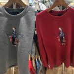 胸元にツイード柄の服を着た買い物中の女性が刺繍されたデザイン。