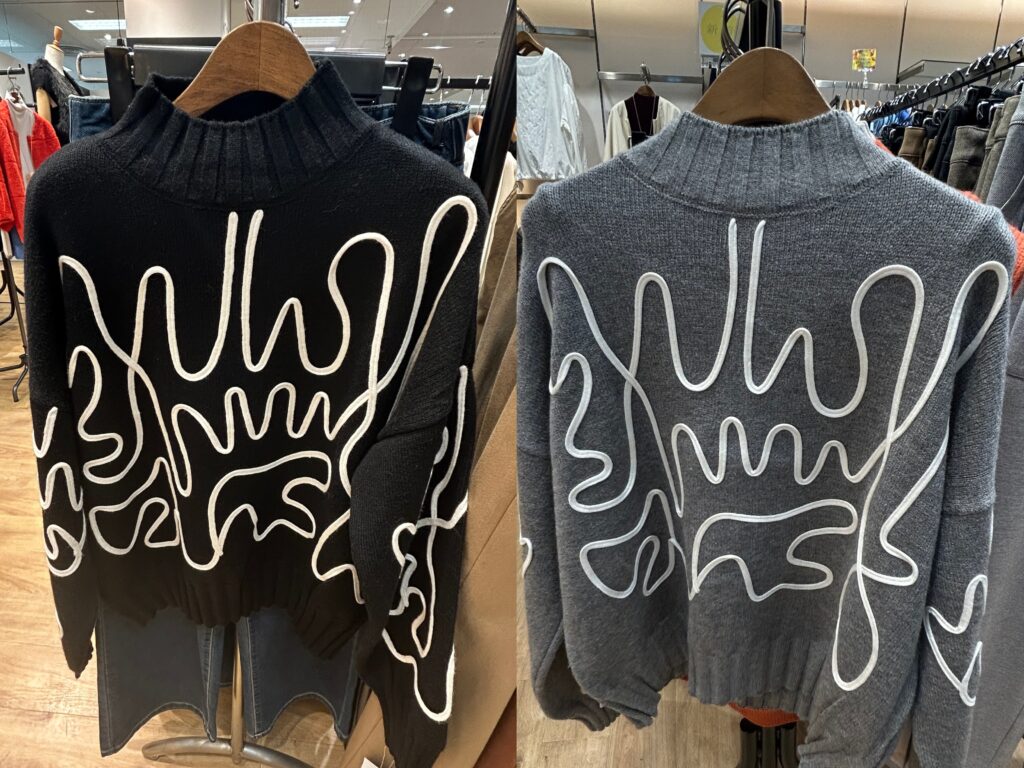 黒とグレーのコード刺繍が施されたヘンリーネックニット