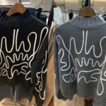 黒とグレーのコード刺繍が施されたヘンリーネックニット