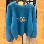 ブルーのモヘアセーターにカラフルな花の刺繍が施された、ふんわり暖かそうなニット