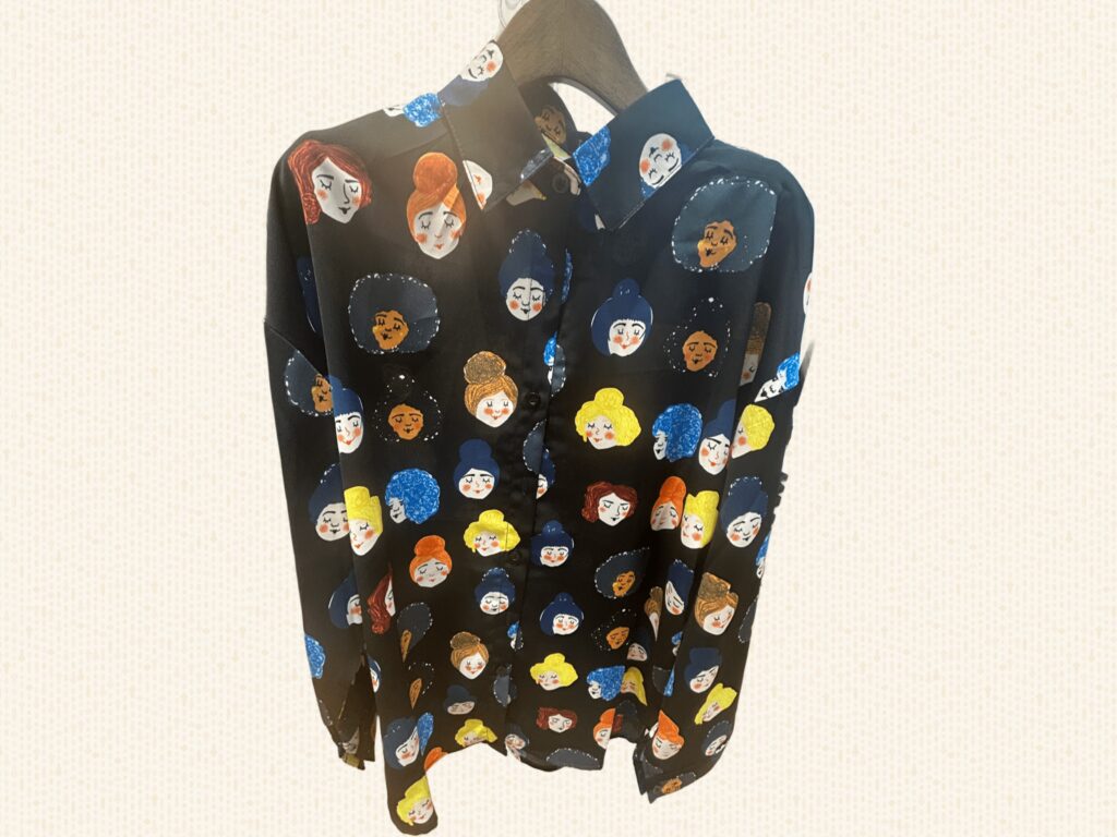 黒地にカラフルな女のひとの顔がプリントされた、長袖シャツ。