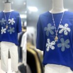 4輪のフラワーモチーフとジルコン装飾が華やかなロイヤルブルーのレディースTシャツ。ゆったり着られるカジュアルトップス。