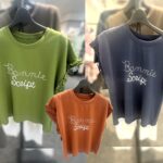 キミドリ、テラコッタ、ネイビーのロゴ入りTシャツ。ふぃ袖口にフリルがあり、深みのあるカラーが秋を感じさせるカジュアルな一着。