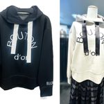 黒とベージュのロゴデザインフードパーカー。長めのドローコードがアクセントになったデザイン。